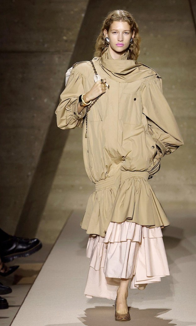 Chloé Spring 2026: beige oversized parka with a smocked flounce at the hem over a pale pink maxi skirt of gathered tiers