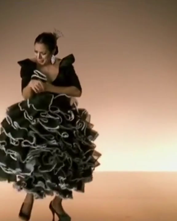 Lola Flores dancing in a black flamenco dress with rows of white-edged volantes, Sevillanas