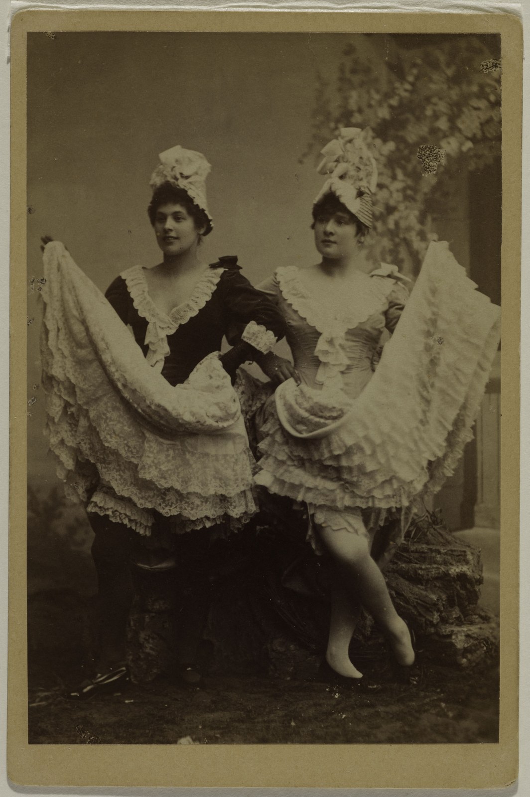 Photograph, 1886: the cancan dancers La Goulue and Grille d’Égout spread their skirts like fans, showing row after row of lace ruffles underneath