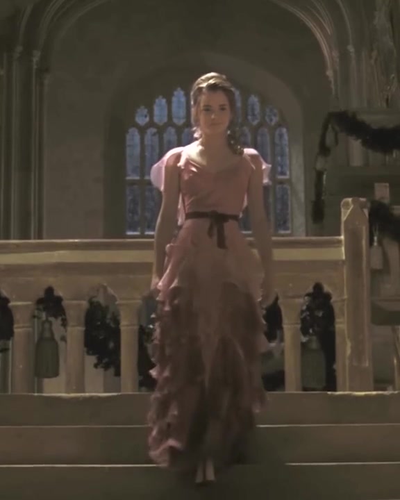 Hermione walks down the staircase to the Yule Ball in a long pink gown with a tiered chiffon skirt, Harry Potter and the Goblet of Fire