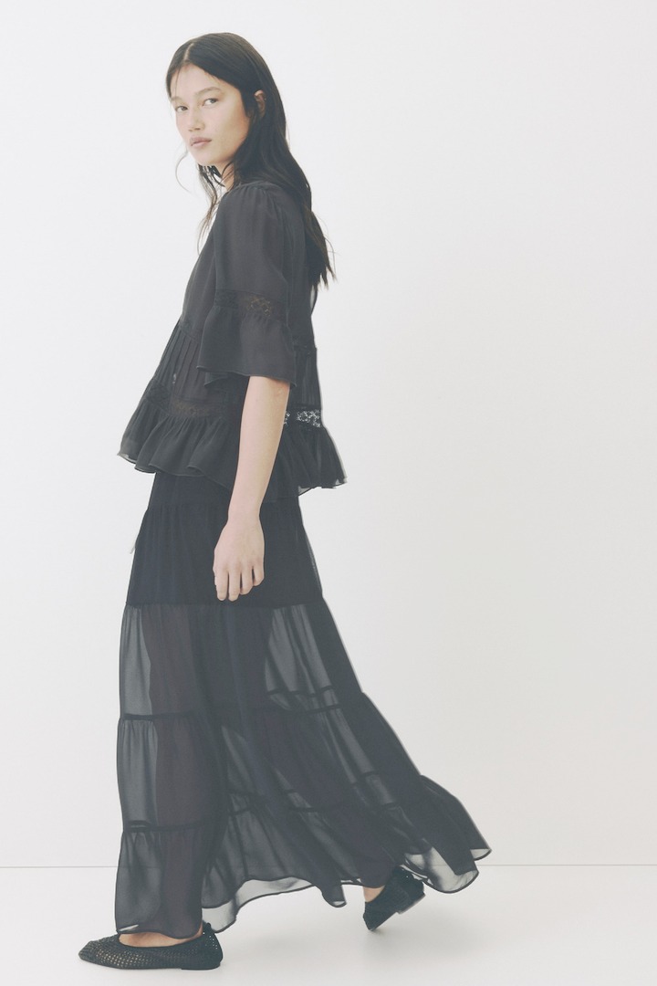 H&M black sheer maxi skirt of gathered tiers, side view while walking
