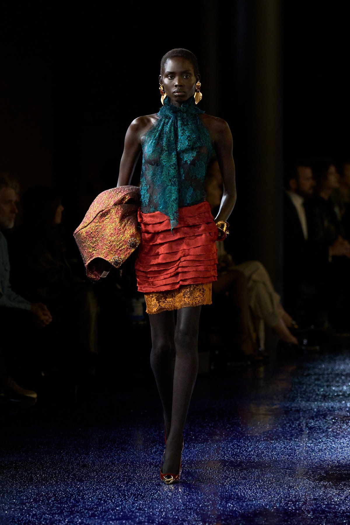 Saint Laurent Spring 2025, look 42: teal lace halter top, rust layered mini skirt over yellow lace, a brocade jacket carried on the arm