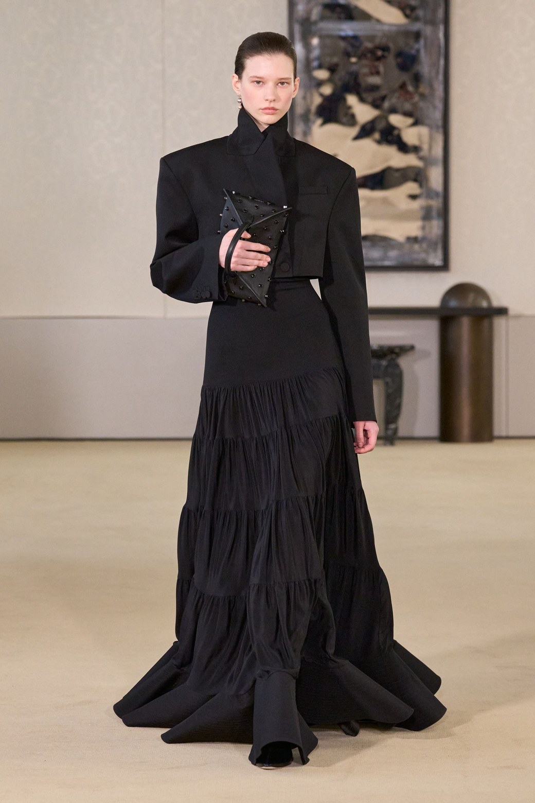 Altuzarra Fall 2026, look 39: black floor-length skirt of three gathered tiers widening to the hem, with a cropped black jacket